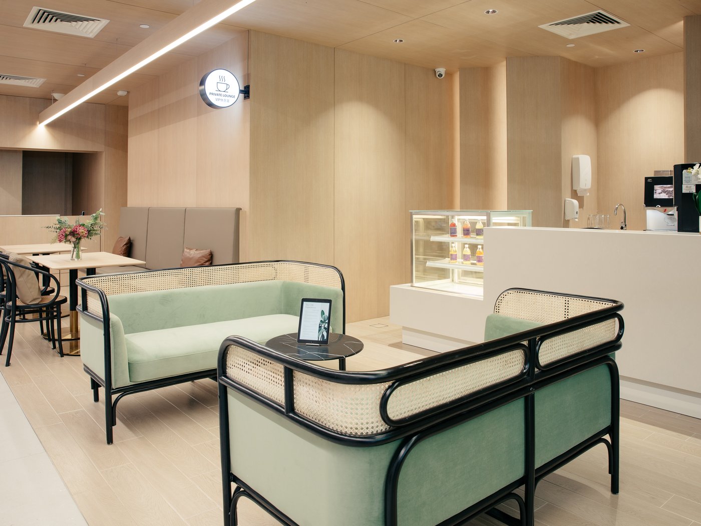 The CSR private patient lounge — mint velvet rattan seating, refreshment counter and quiet workspace.